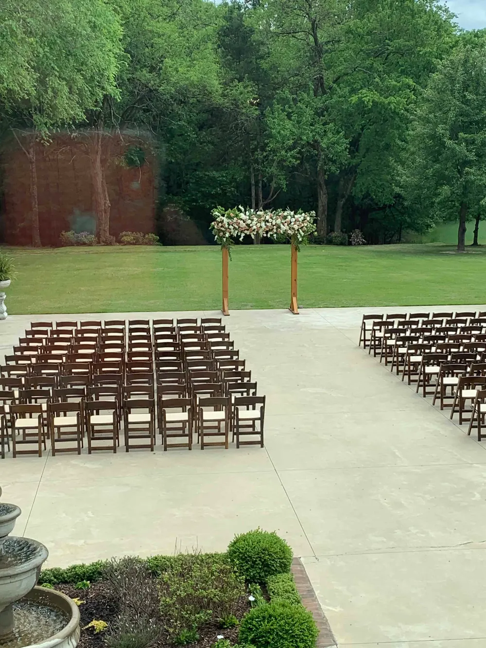 Outdoor ceremony with rows of chairs and a floral-topped arch