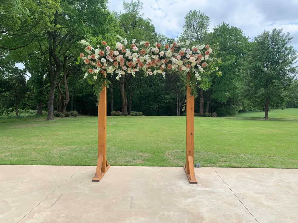Wooden ceremony arch crowned with white and green florals