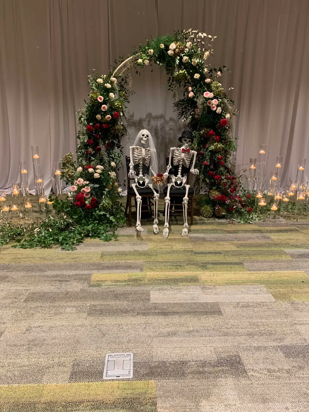 Halloween floral installation with seated skeletons and candles