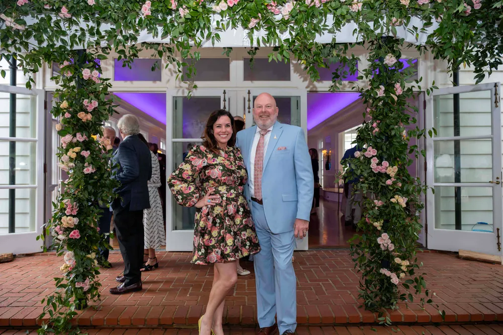 Guests arriving beneath a floral entrance installation